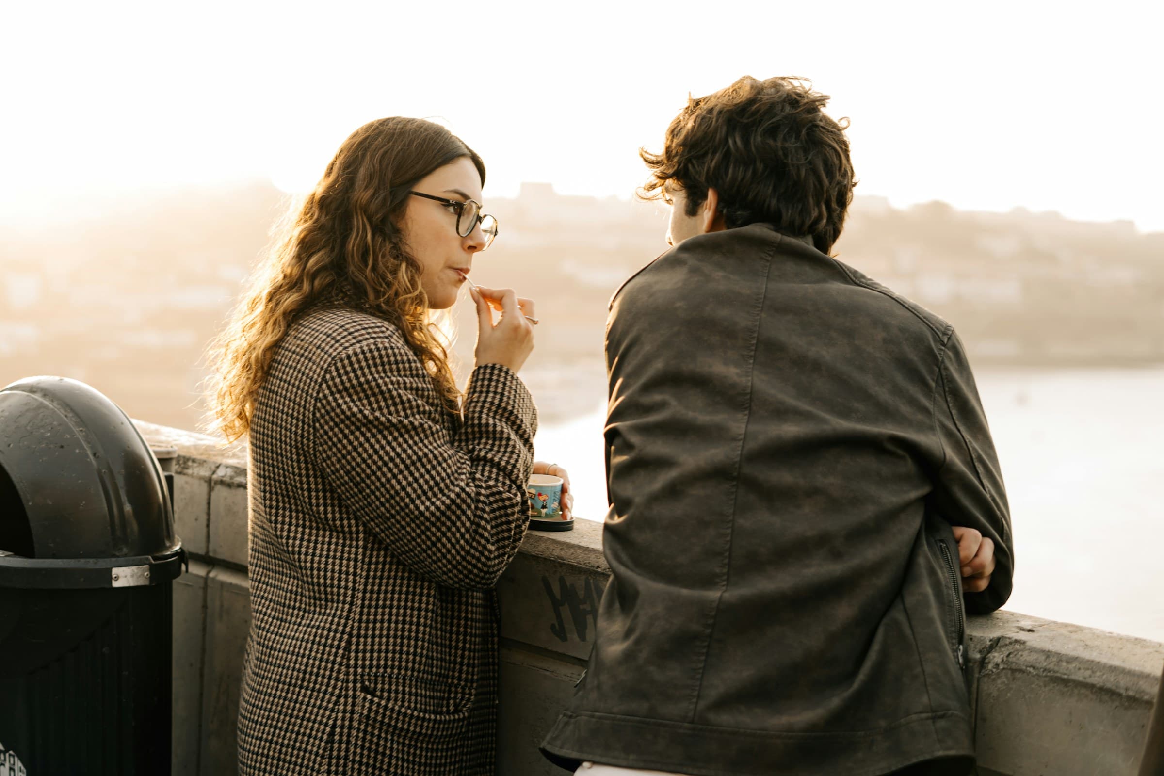 Two people with coffee, looking out over the water